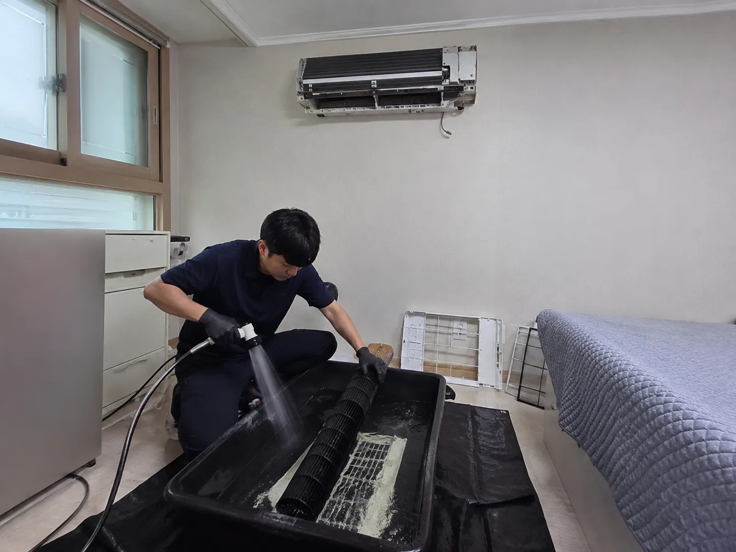 분리한 에어컨 커버와 필터를 세척하는 작업 과정